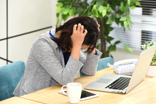 パソコンの前で悩む若い女性