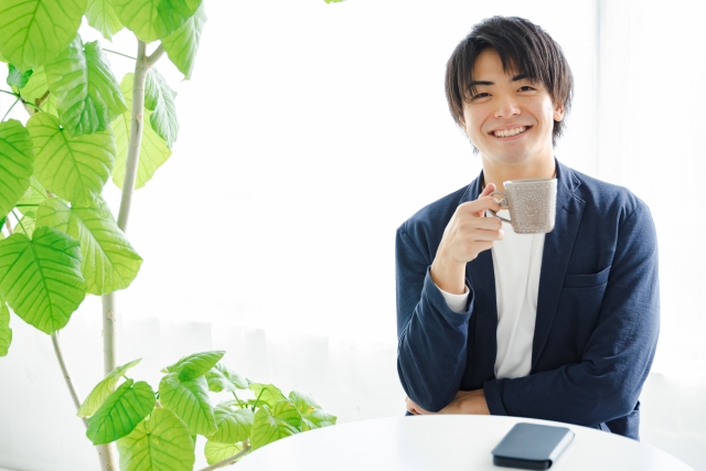 飲み物を持ってこちらを見る笑顔の男性