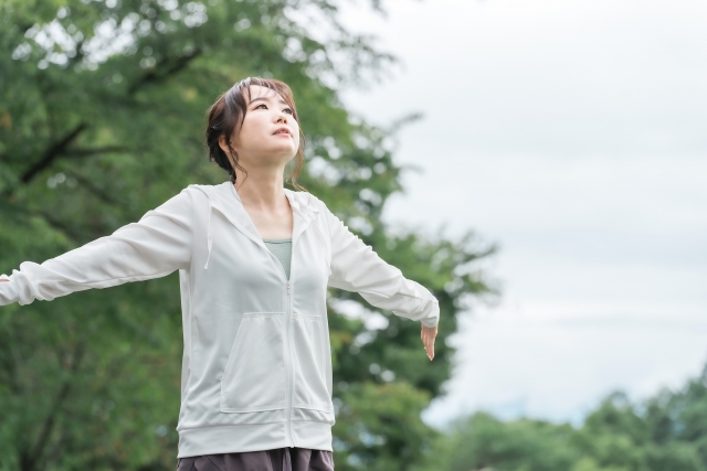 公園で深呼吸するジャージ姿の女性