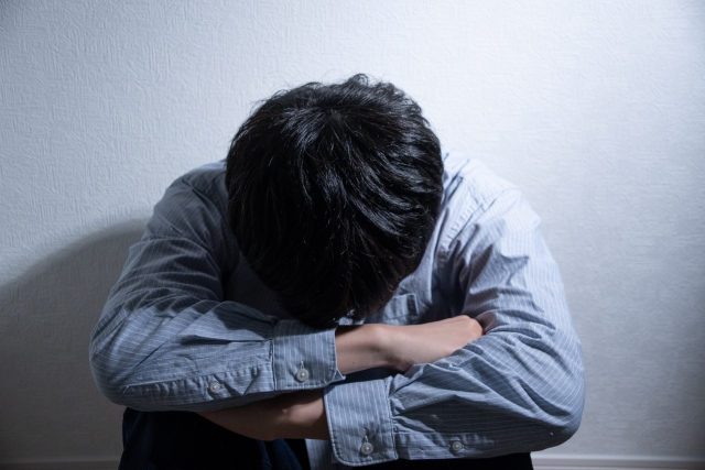 うずくまり落ち込む男性とスポットライト
