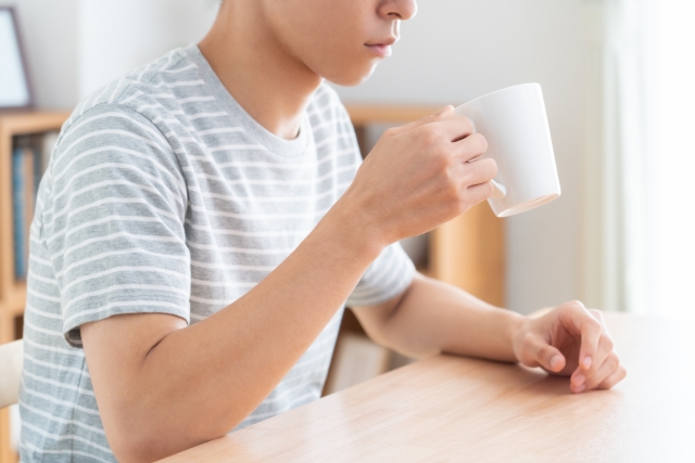 リビングでドリンクを飲む男性