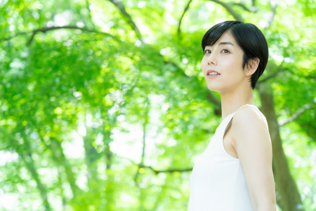 緑の中でスキンケアをする若い女性