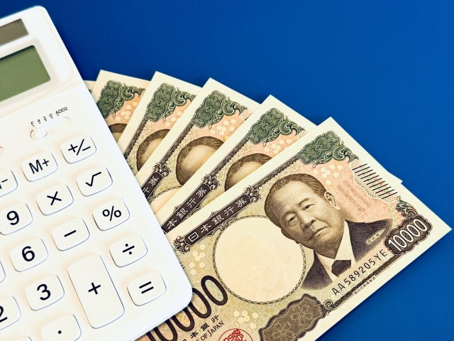 白い電卓とお金（青背景）
