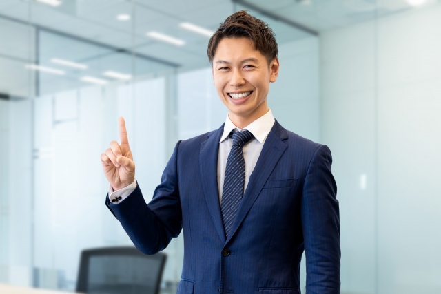 人差し指を立てて案内する男性ビジネスマン