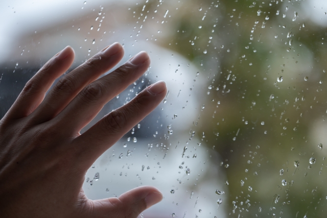 雨粒の窓に置かれた女性の手