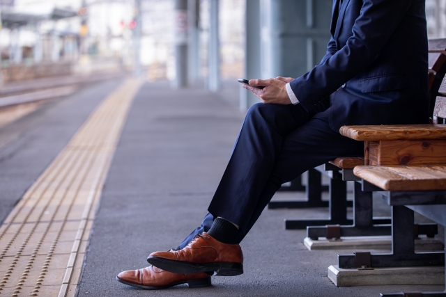駅のホームで携帯電話を操作する男性