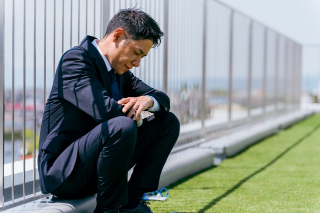 屋上で落ち込むビジネスマン（疲労・失業）